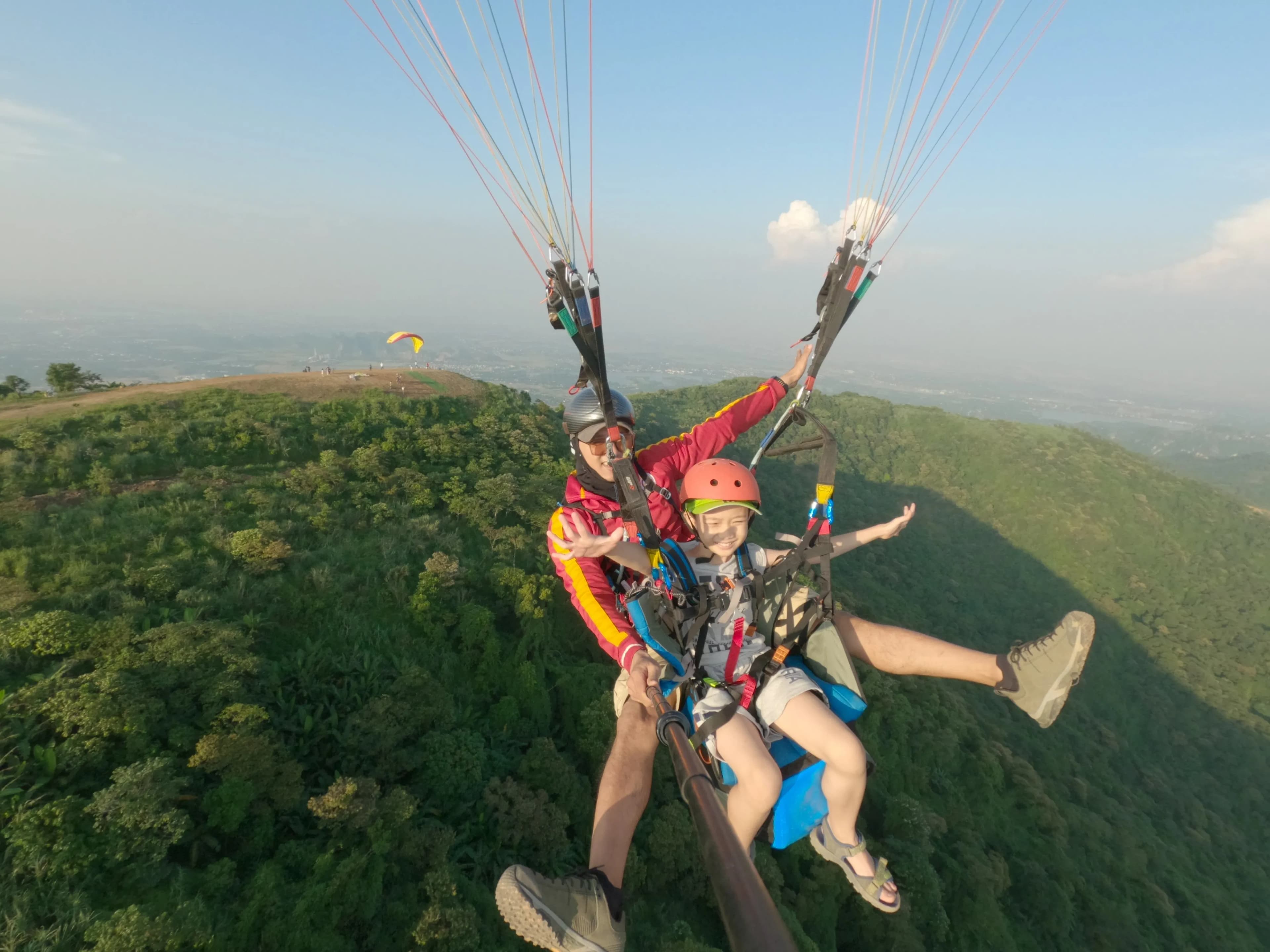 What is the best season to experience paragliding in Hanoi?