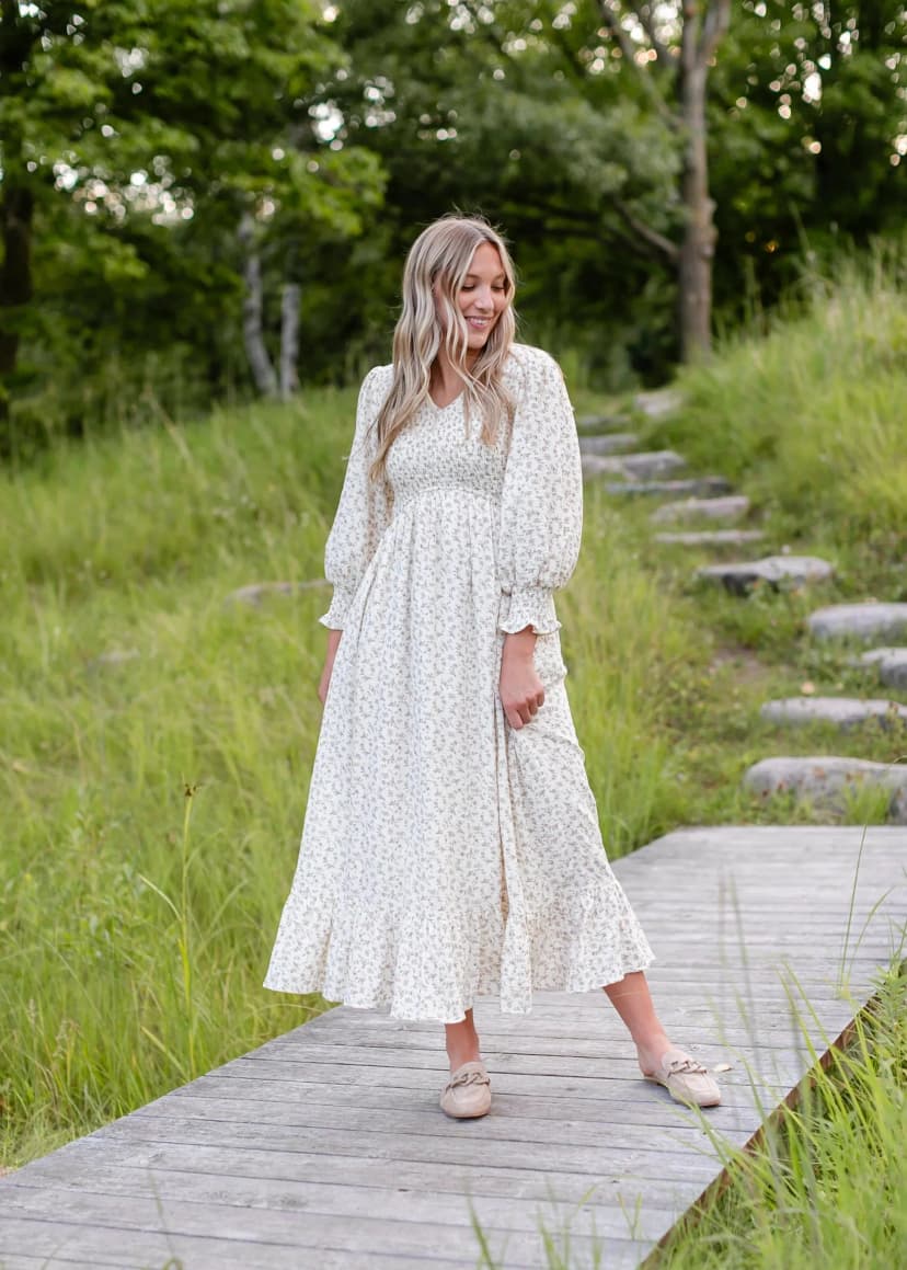 A long-sleeve floral smocked maxi dress with a flattering fit, featuring a vibrant floral pattern, a fitted bodice, and flowing skirt, offering both elegance and comfort