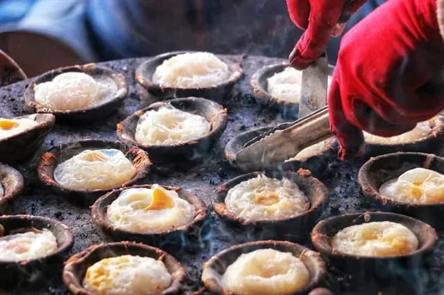 Crispy Banh Can being cooked in traditional clay molds.