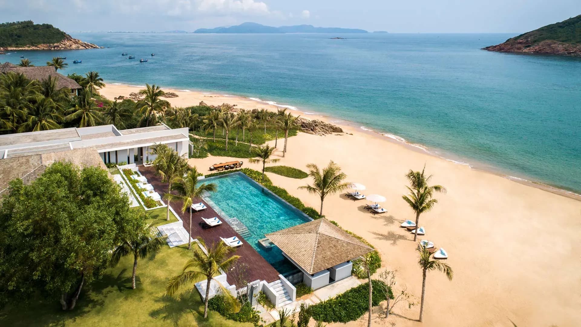 Beachfront view with golden sands and pool at Anantara Quy Nhon Villas, perfect for a tranquil getaway.